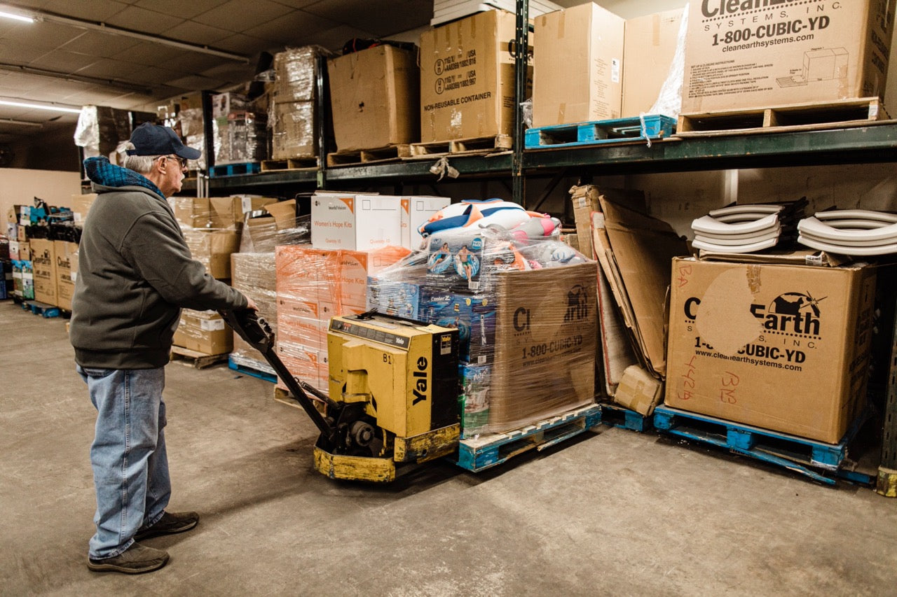 A man uses a tool for moving materials around in a warehouse